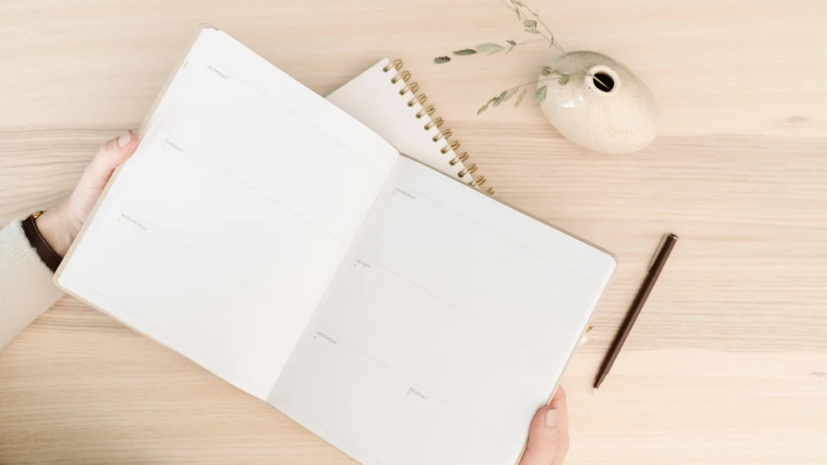 Open calendar with pencil and small vase.