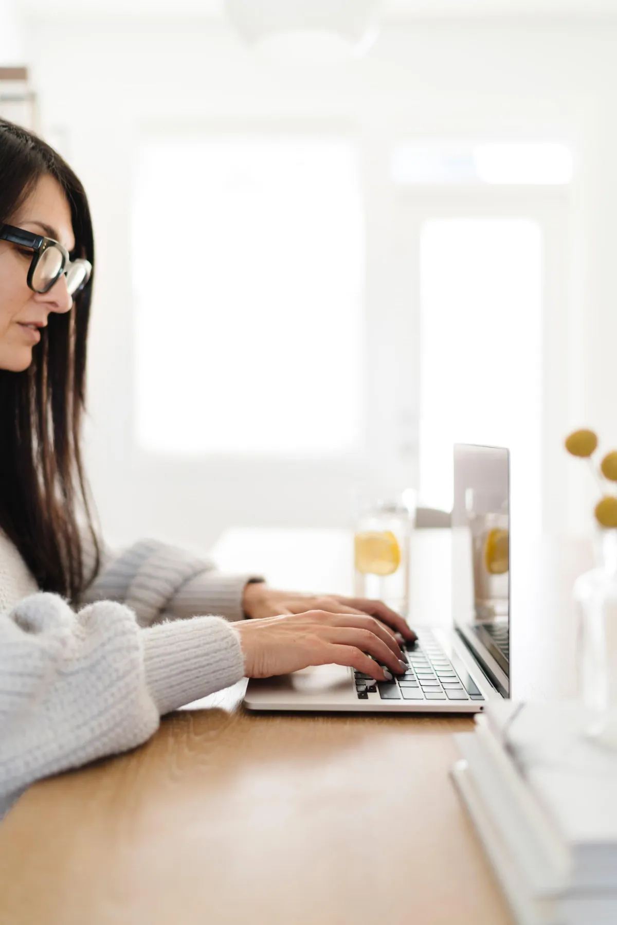 Midlife woman typing on a computer alone.