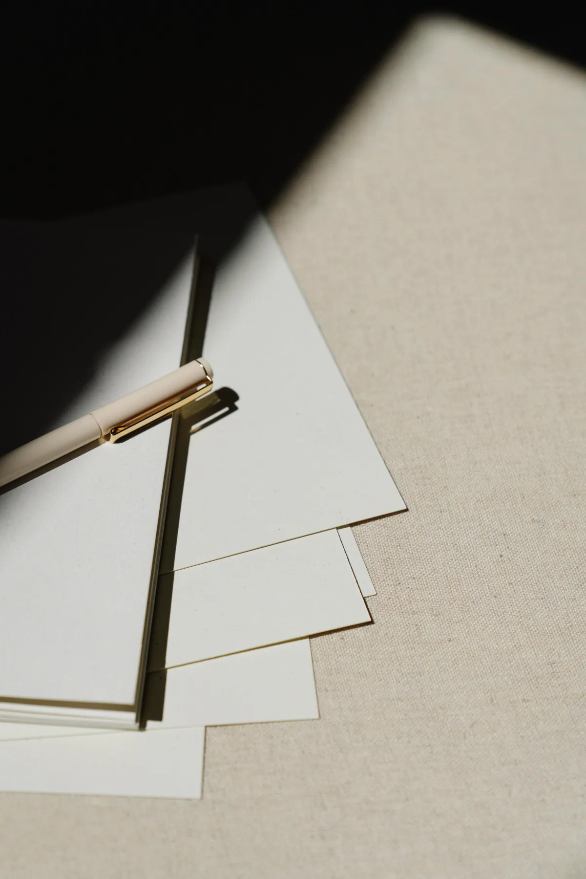 Pen on top of pieces of paper in a dark shadow.