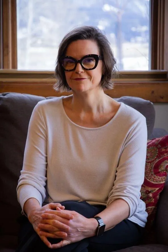 Book coach Maurene Janiece sitting at a wood table.