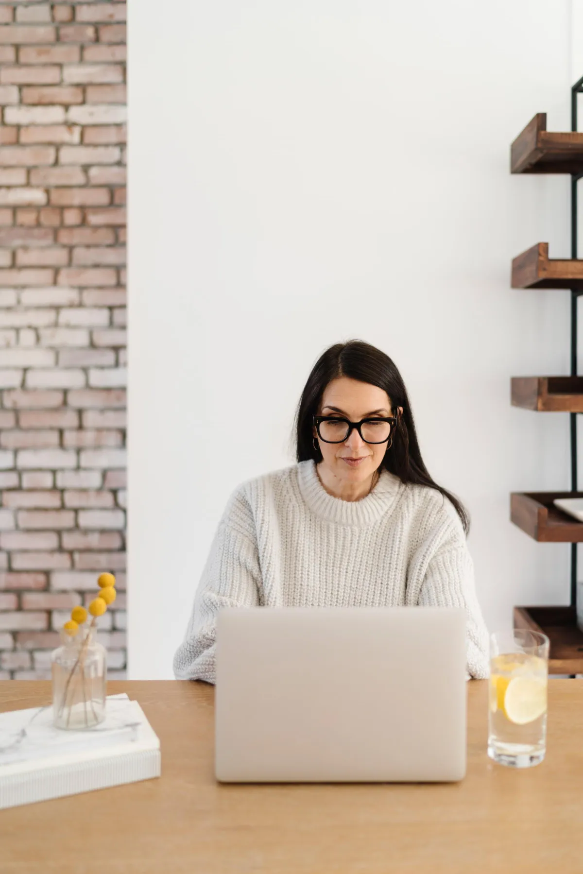 Midlife woman sitting in front of a laptop and smiling during a book coaching call.