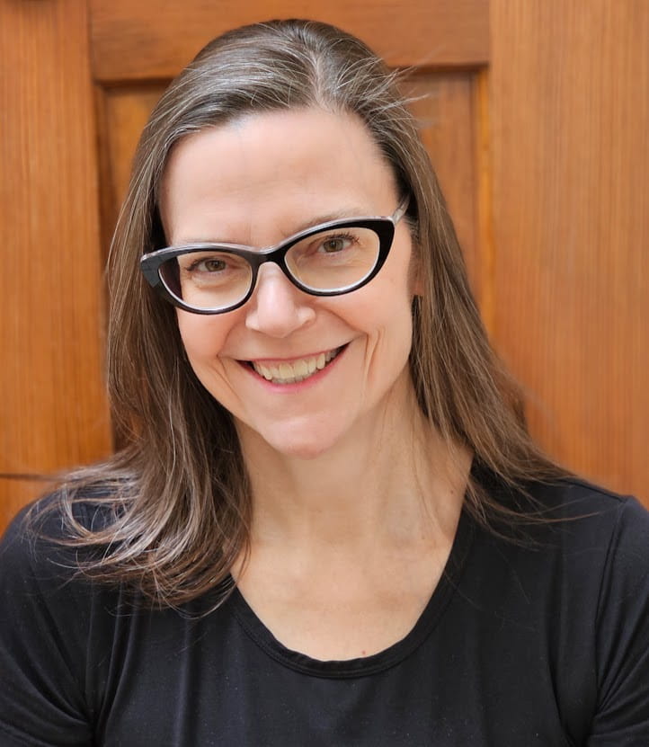 Book coach Maurene Janiece sitting at a wood table.