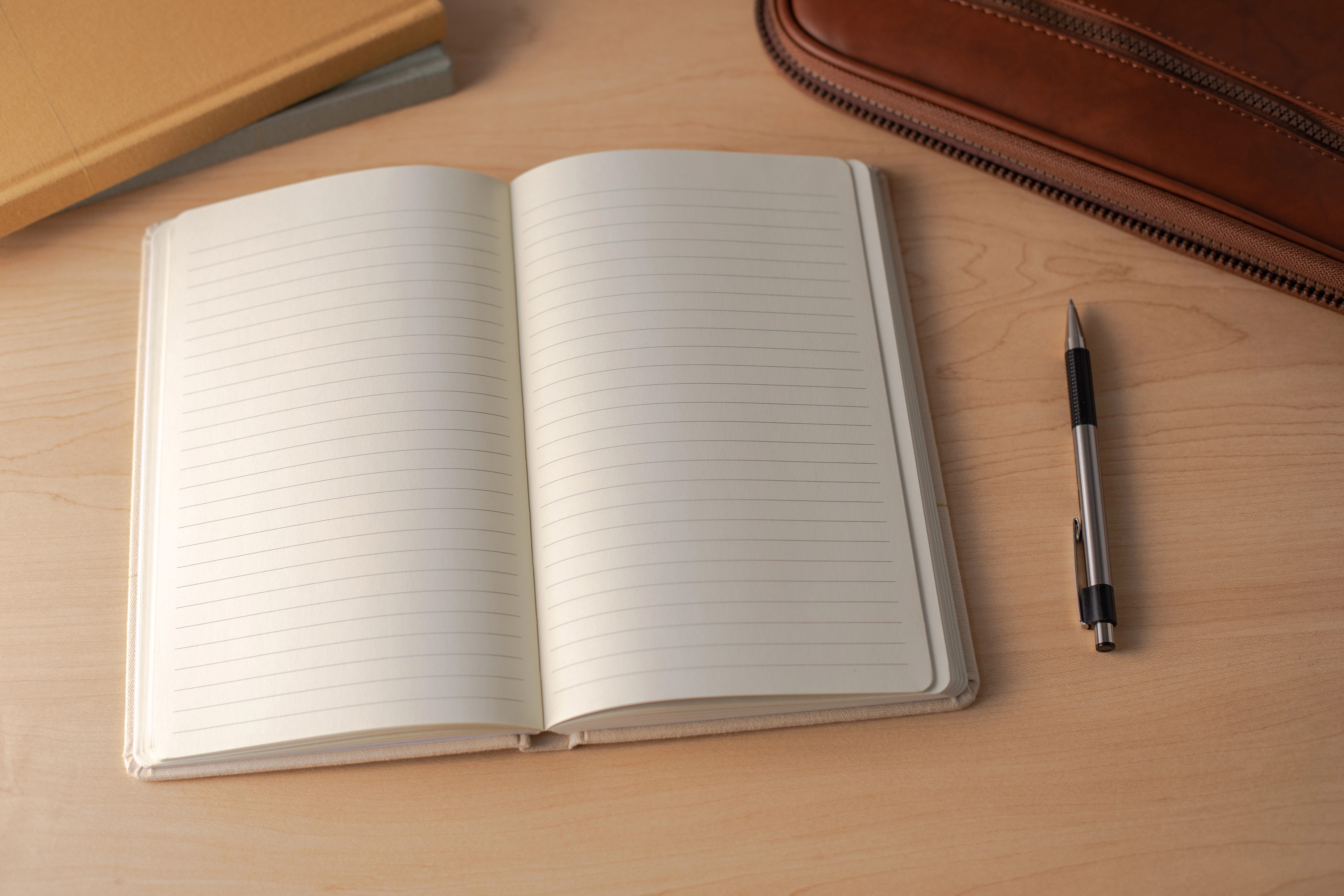 Open blank notebook and pen on a tan desk