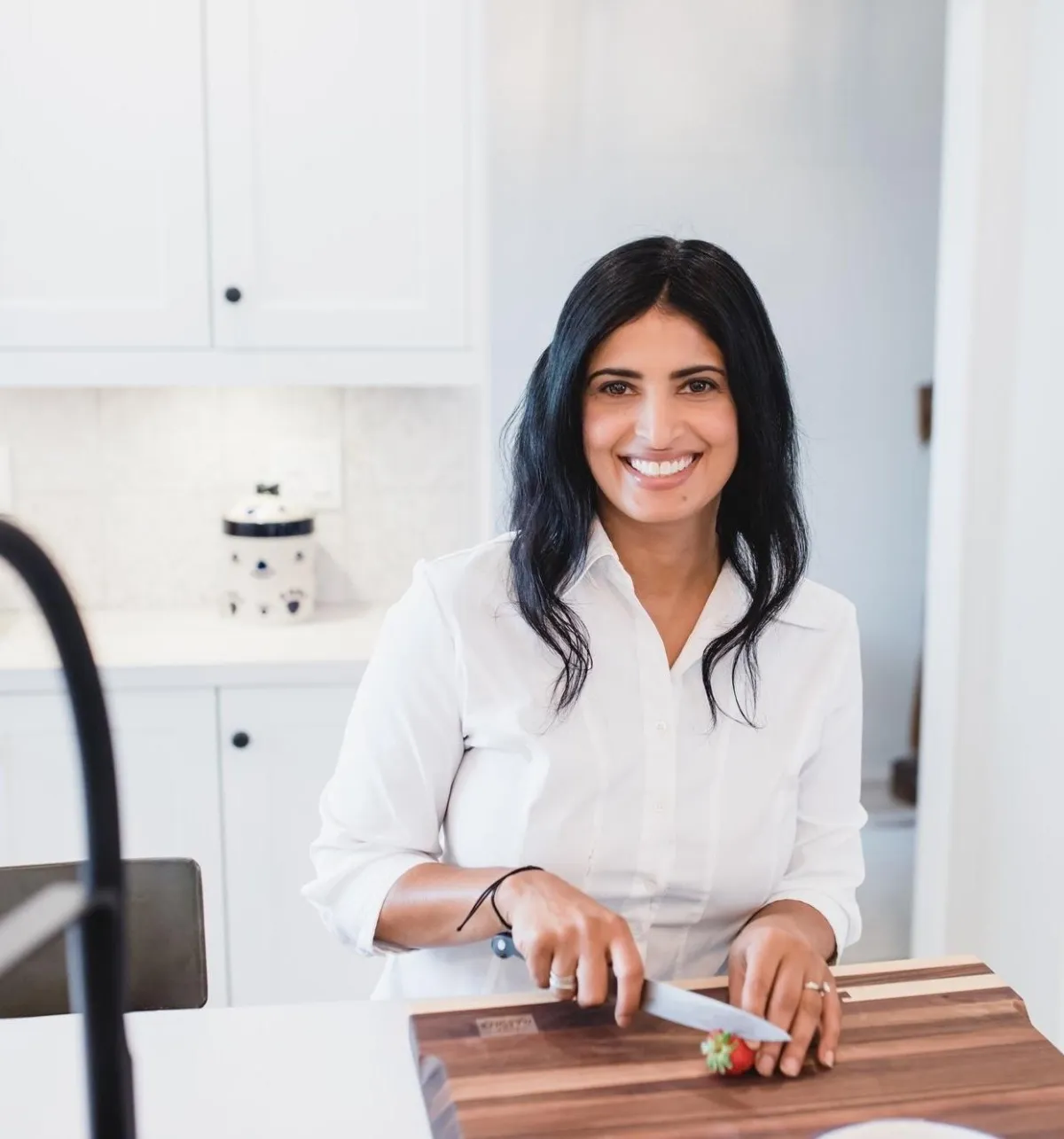 Julie Brar smiling in her kitchen preparing food