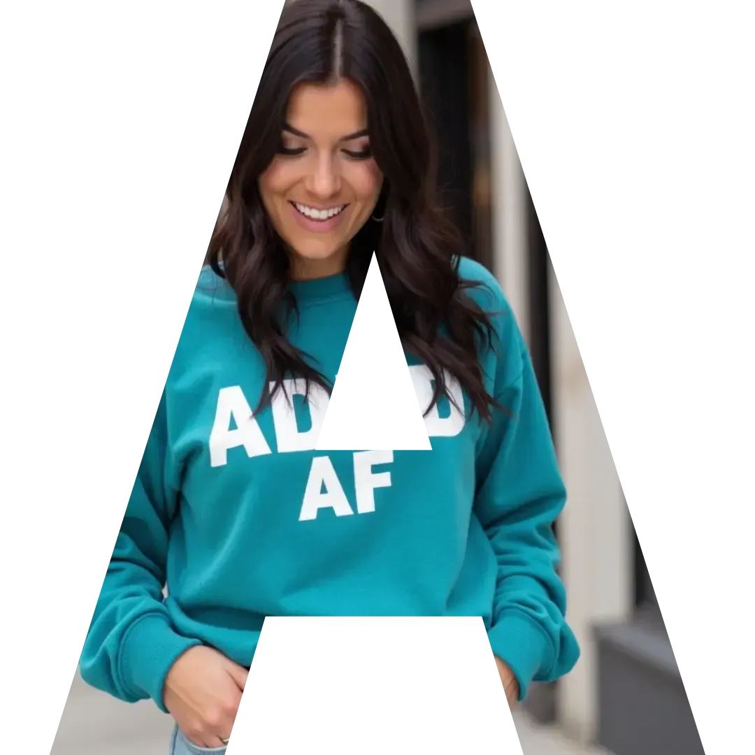 Alyece Smith smiling while looking down, wearing a teal ‘ADHD AF’ sweatshirt, layered inside the letter A—used for branding the ADHDpreneur Academy.