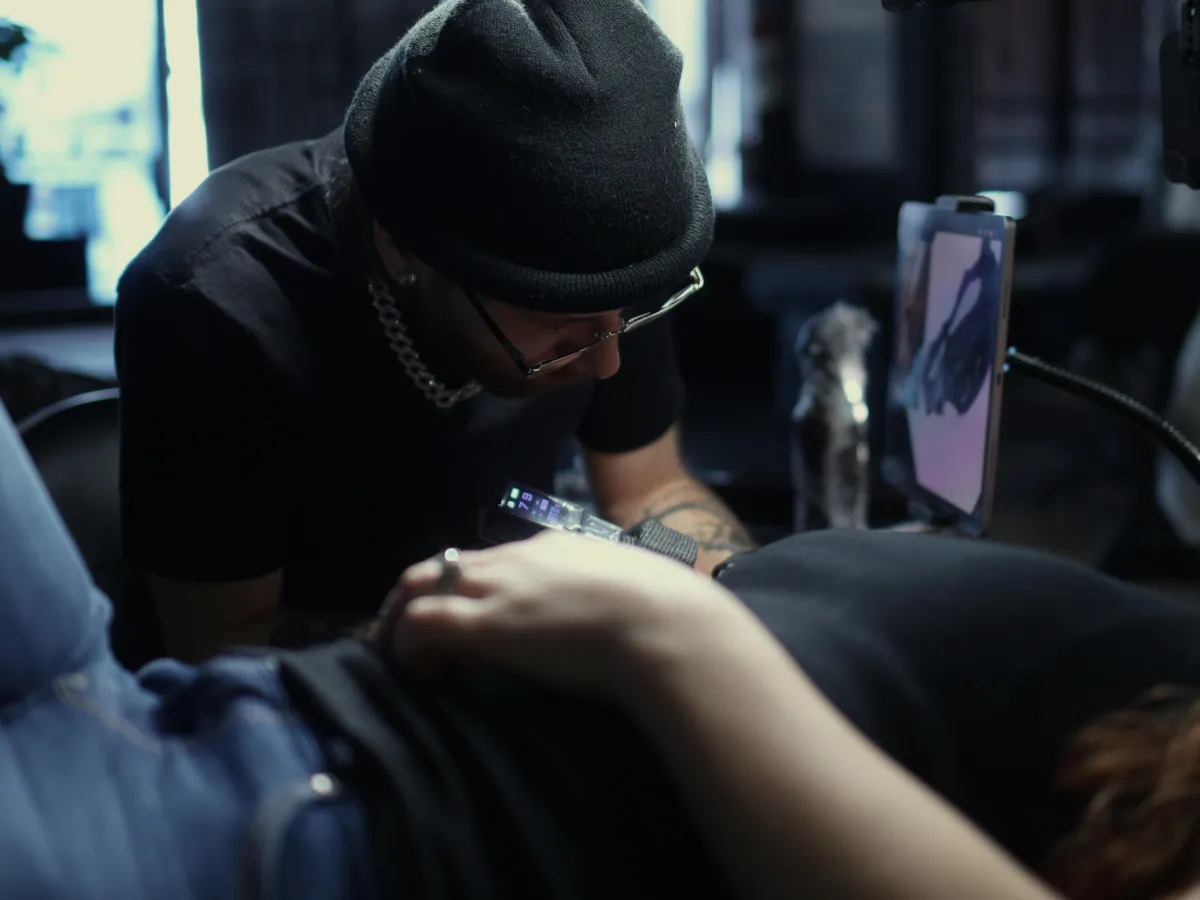 Black and grey realism and surrealism tattoo artist in Warren, Ohio creating a custom high-detail tattoo in a professional studio, using a reference image to deliver clean, high-contrast realism and surreal tattoo work.