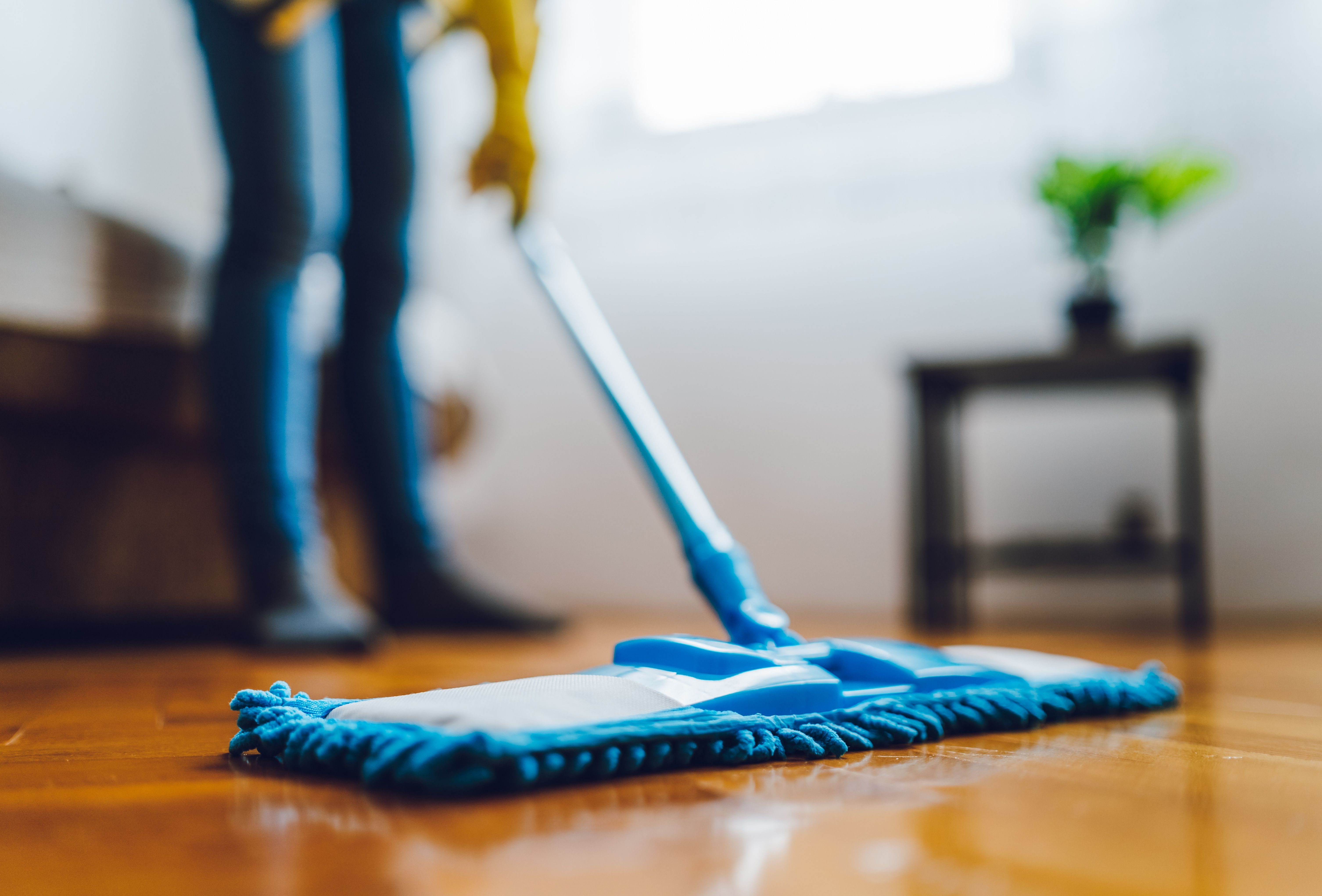 A blue mop cleaning a wooden floor, showcasing results from a cleaning service near me.