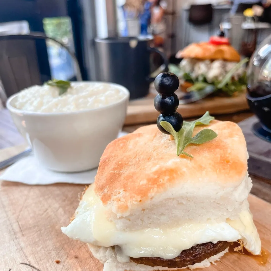 Gourmet sausage, egg, and cheese biscuit sandwich with grits for brunch at Rushing Trading Co. in Johns Creek, GA