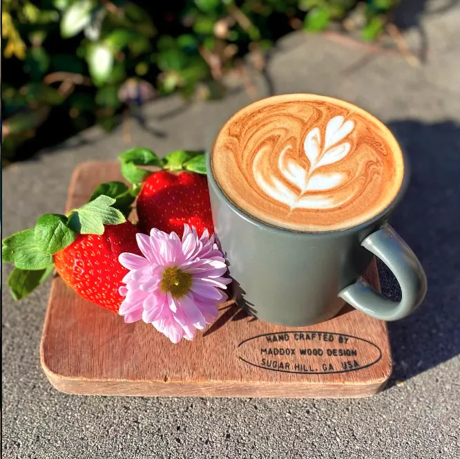 Small-batch latte with rosette latte art and fresh strawberries at Rushing Trading Co. in Johns Creek, GA