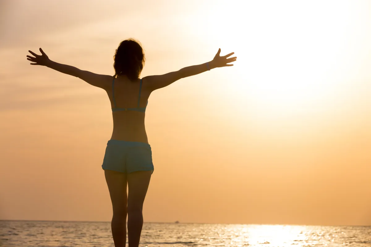 Joyful woman outdoors with raised arms symbolizing self-worth and freedom.