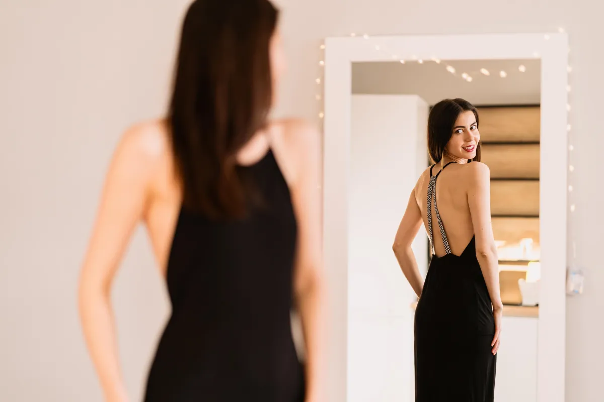 Smiling woman looking in mirror, representing confidence hypnosis
