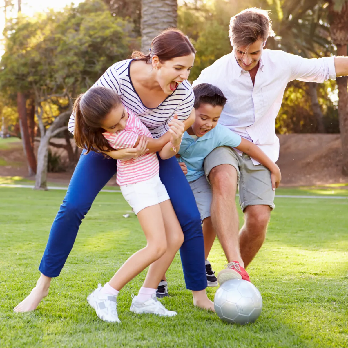Happy family playing soccer together outdoors, symbolizing screen-free connection and real-life bonding.