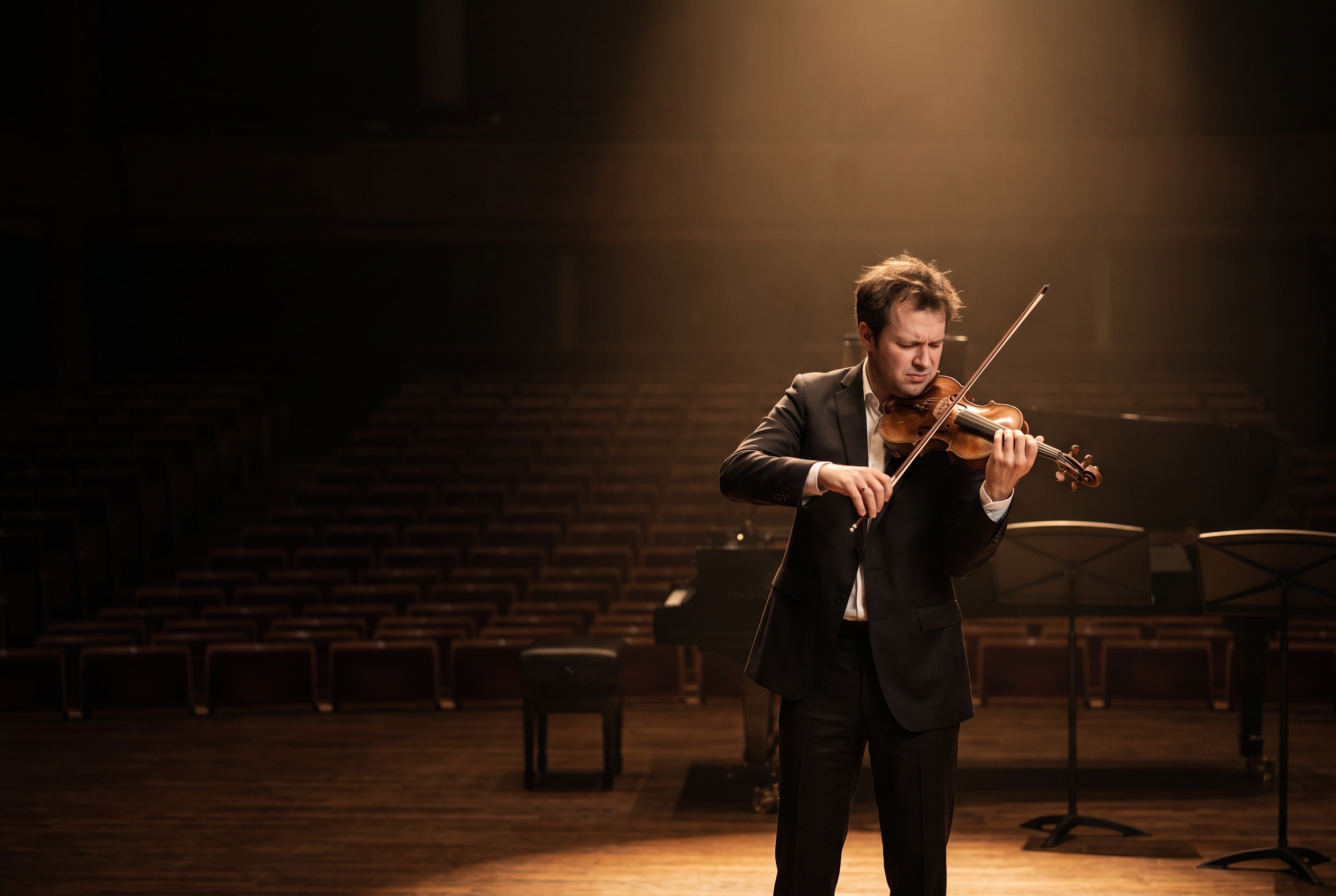 Violinista con miedo escénico actuando en solitario bajo la luz del escenario
