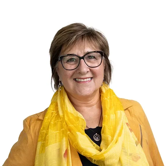 Professional headshot of a smiling real estate agent wearing glasses and a yellow scarf on a clean white background