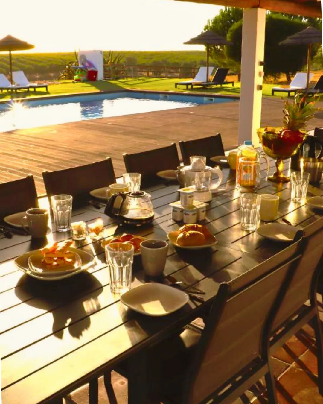 Mesa posta ao ar livre no Monte da Figueira Brava, com vista deslumbrante para a piscina e paisagens do Alentejo, oferecendo um ambiente elegante e acolhedor para refeições memoráveis ao sol.