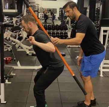 Personal trainer guiding a client in an exercise.
