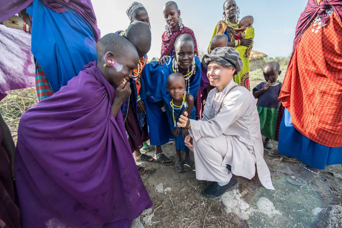 Photographer sharing cell phone image with Maasai children in Tanzania, Africa