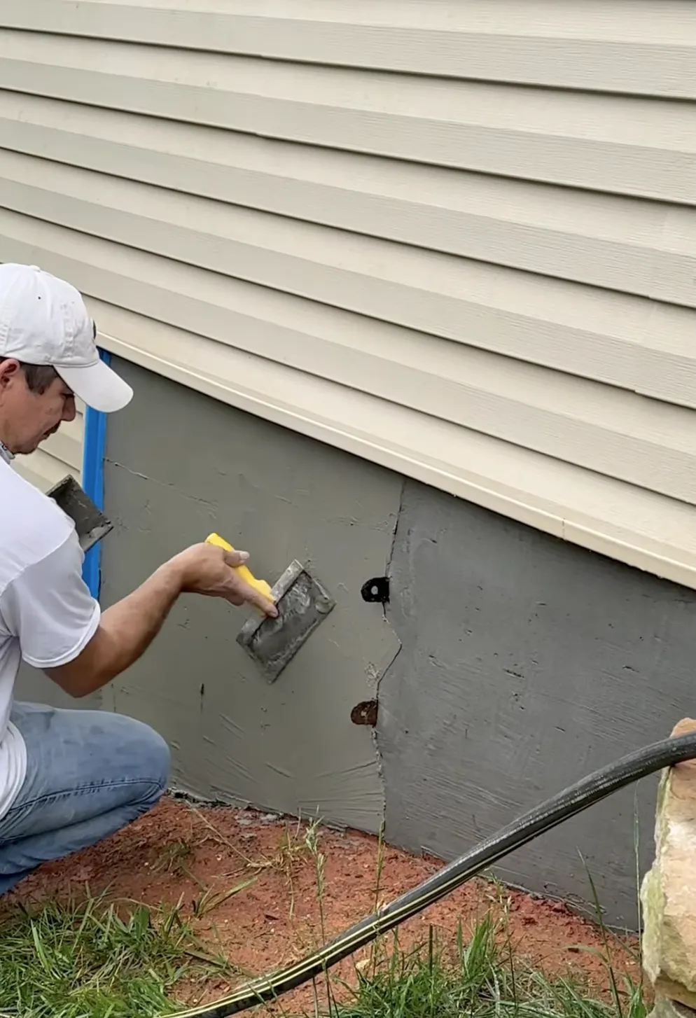 man smoothing over stucco on the bottom of the house