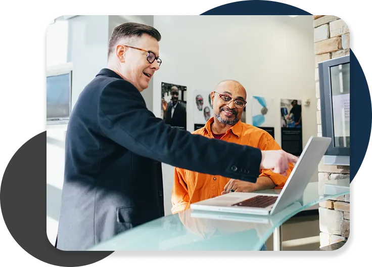 Businessman showing laptop screen to client in office.