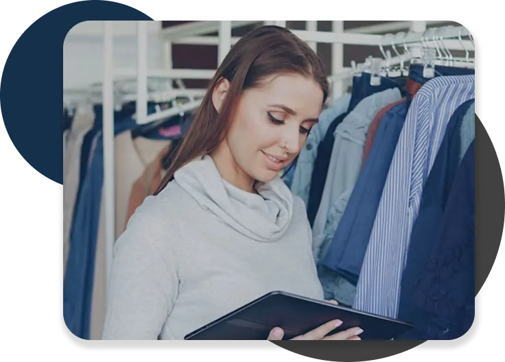 Woman using a tablet while standing in a clothing store.