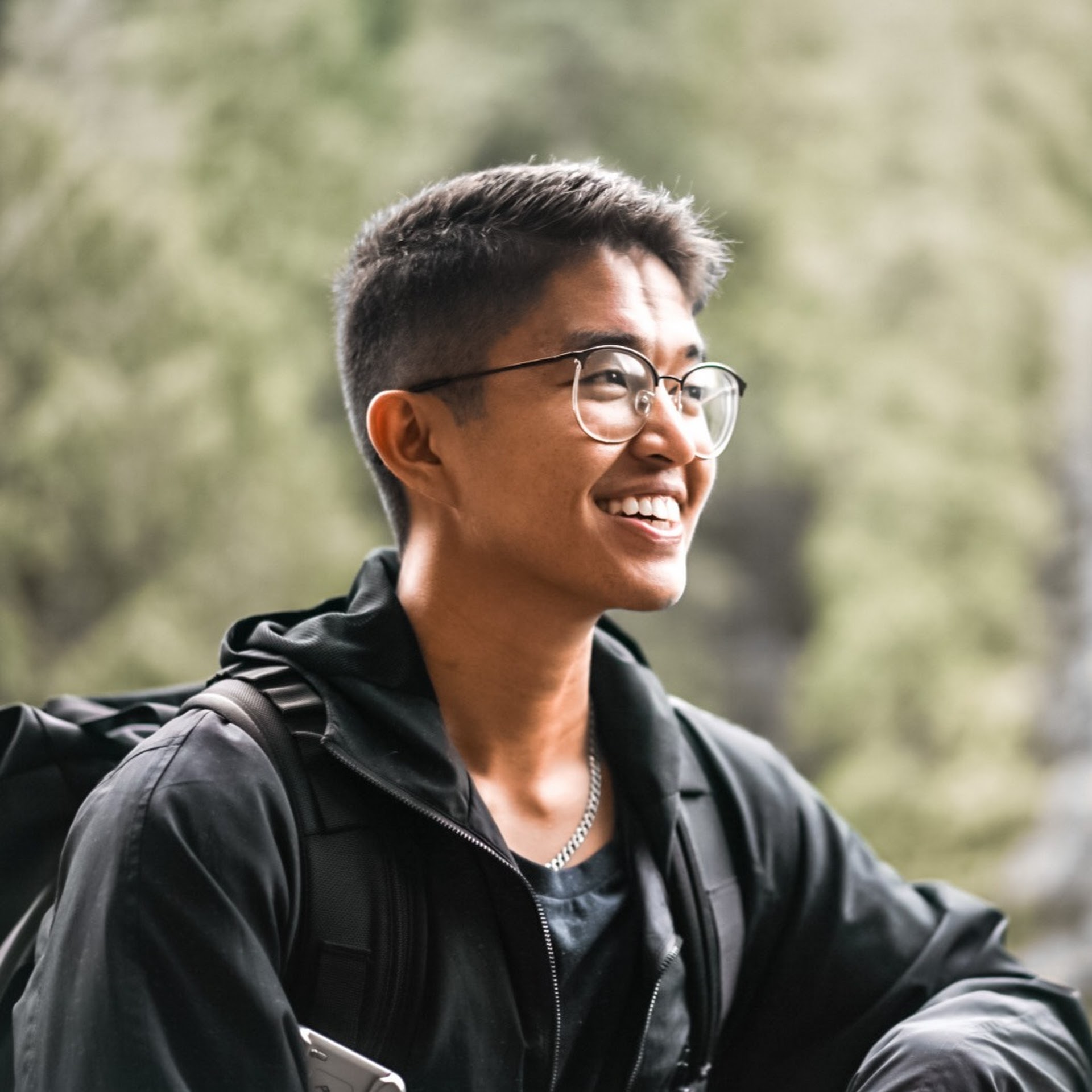 A small business owner, mid-30s, South Asian woman, sits at a café table with a laptop, looking thoughtfully at marketing charts. The setting is bright and airy, with plants and a city street visible through the window, conveying contemplation and determination.