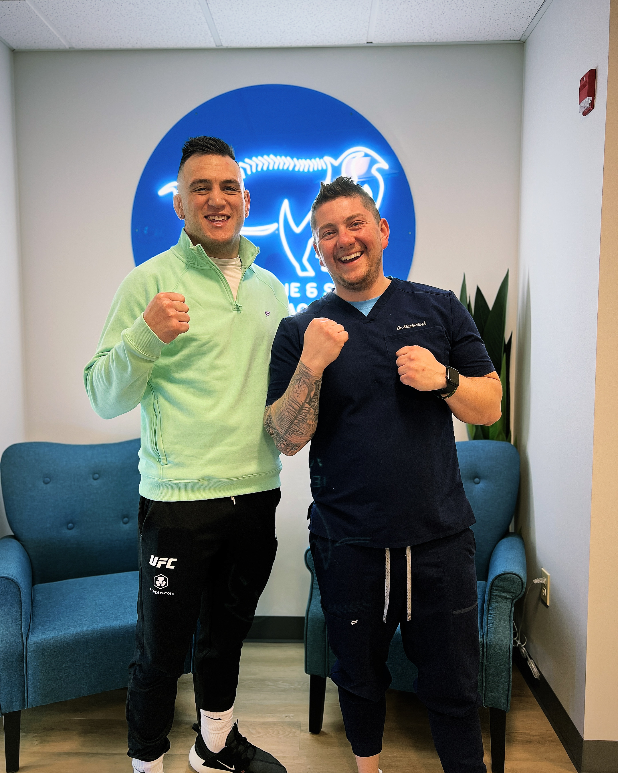 A smiling middle-aged woman sitting comfortably in a bright living room, holding a yoga mat. She appears relaxed and content, symbolizing improved mobility and well-being after chiropractic care. The background is softly blurred, focusing on her positive expression.