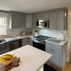 Remodeled kitchen with gray shaker cabinets, quartz countertops, and tile backsplash in Worcester, MA by ARM Construction