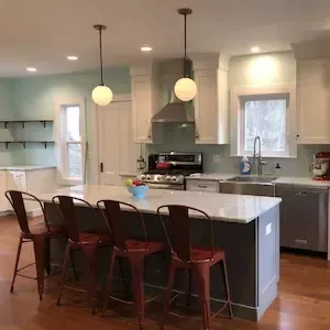 Remodeled kitchen with white cabinets, quartz island, and open shelving by ARM Construction in Worcester, MA