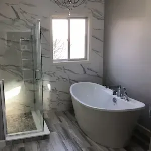 Remodeled bathroom with marble-look tile, freestanding soaking tub, and glass walk-in shower by ARM Construction in Princeton, MA