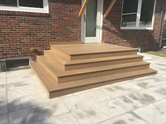 Composite deck stairs and landing over a paver patio, built by ARM Construction in Holden, MA