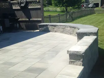 Bluestone patio with a curved granite seating wall, built by ARM Construction in Shrewsbury, MA