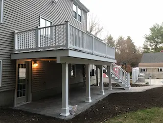 Second-story deck with a covered patio and stone landing below, built by ARM Construction in Worcester, MA