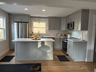 Remodeled kitchen with gray shaker cabinets and a quartz island, by ARM Construction in Worcester, MA
