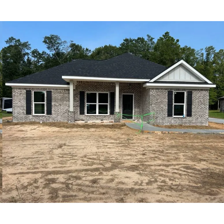 Exterior of new build home on sand. Gray rancher style home with black pitched roof.