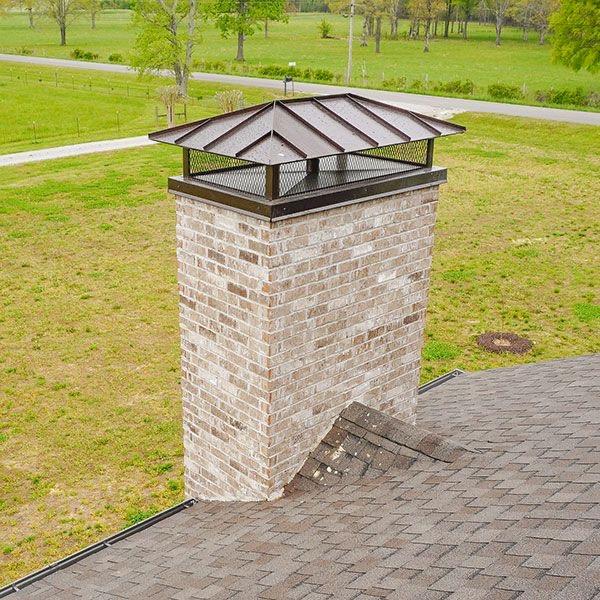 Photo of a restored brick chimney on a roof in front of green lawn