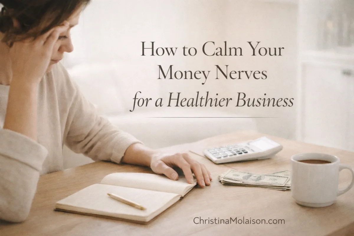 Female entrepreneur managing business finances with a notebook and calculator in a calm workspace, illustrating how to reduce money anxiety, improve financial clarity, and build a healthier business.