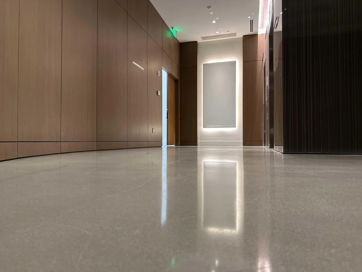 Residential kitchen with a light blue, high-gloss epoxy floor, white cabinetry, and stainless steel appliances. The floor’s shine and color create a vibrant, modern atmosphere, demonstrating the visual impact of professional floor coating.