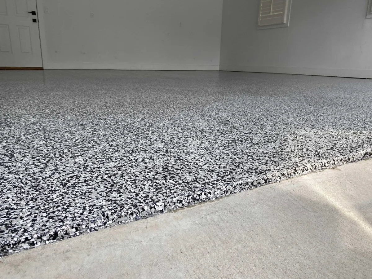 Industrial warehouse with a smooth, durable gray epoxy floor, large open space, and organized shelving. The flooring’s even finish and resilience highlight the suitability of epoxy for demanding commercial environments.