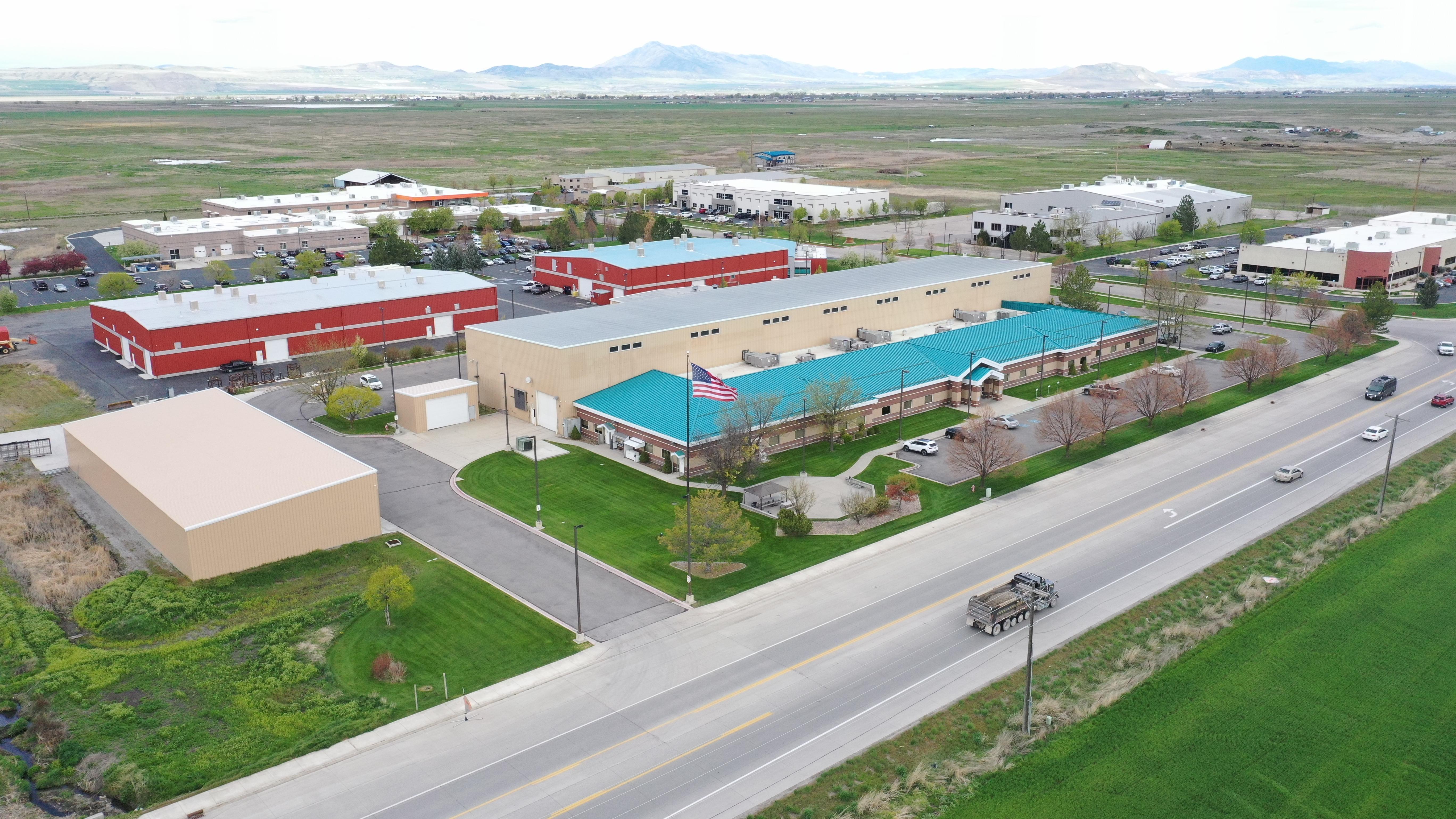 Aerial dusk photograph of a two-building industrial campus on 1.86 acres, shot from 200ft with soft golden-hour light, wide composition showing rooftop details and surrounding streets.