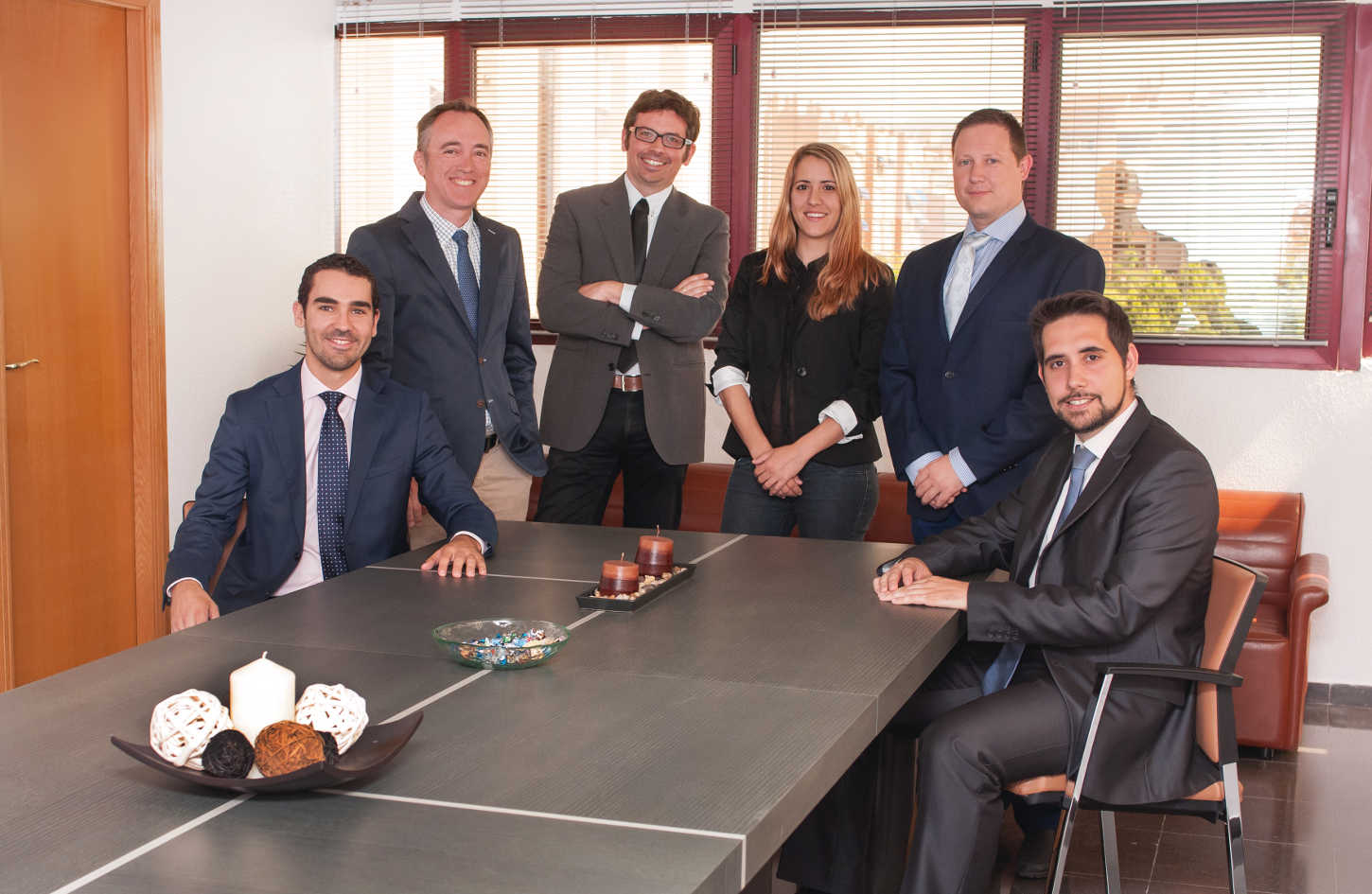 A close-up of a legal expert's hands typing on a laptop, telecom law books and a smartphone beside them, with a digital map of global telecom networks on the screen. The workspace is bright and modern, with blue accents.