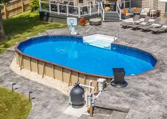 Oval above-ground swimming pool with vinyl liner, steps, and surrounding patio deck in a backyard.