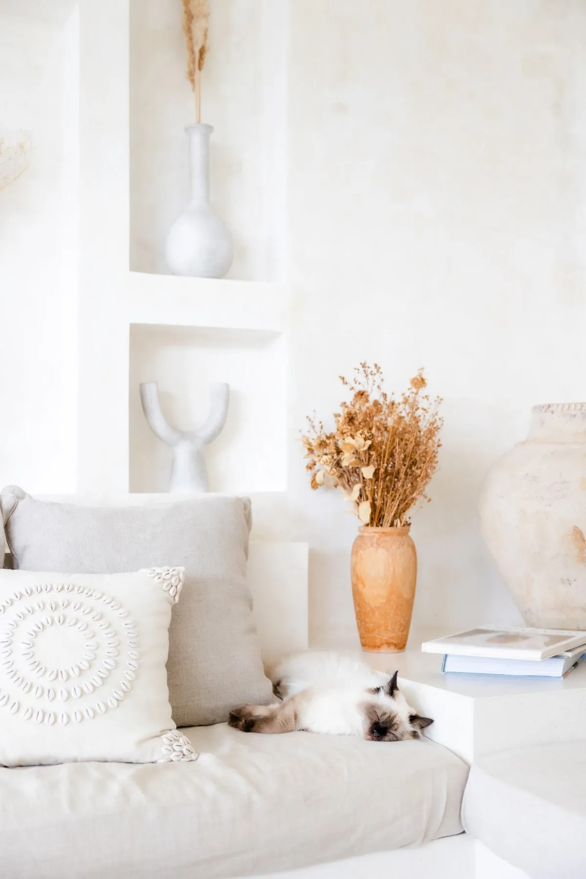 Warm neutral living room with layered textures, organic pottery, soft textiles, and natural light — calm sanctuary interior design