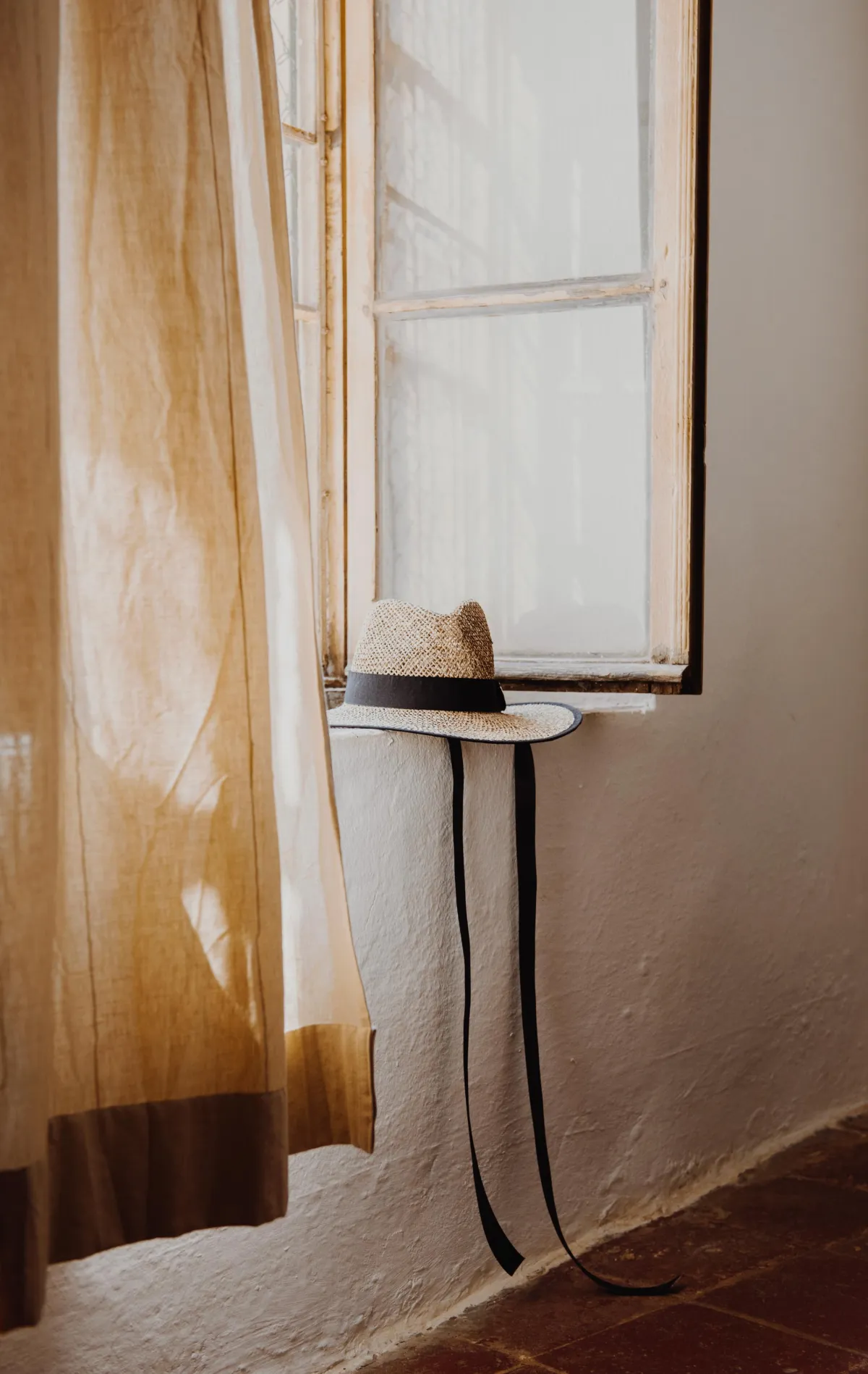 Sunlit minimal interior with hat on window ledge and serene soft textures