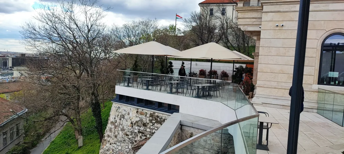 Panorámás várterasz bézs napernyőkkel és üvegkorláttal