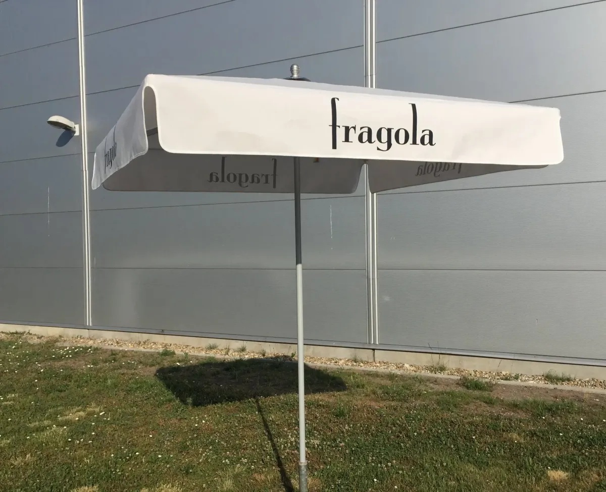 Fehér, szögletes Fragola napernyő ipari épület előtt.