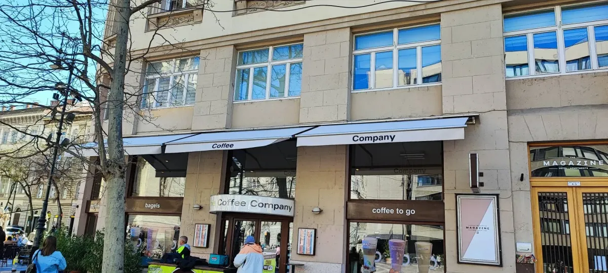 Logózott könyökkaros napellenzők egy belvárosi kávézó homlokzatán