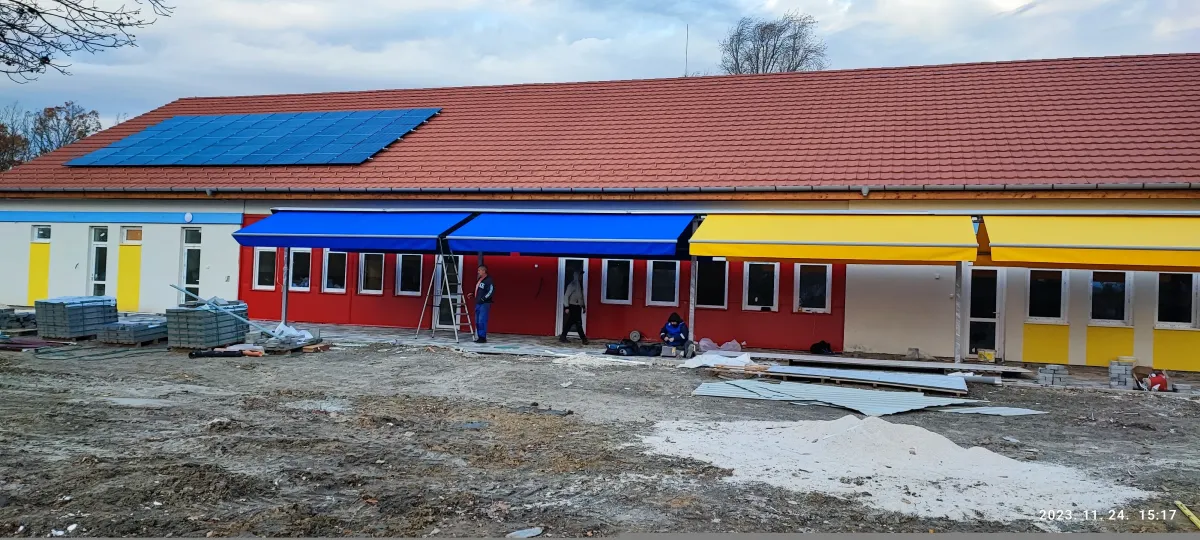 Építés alatt lévő kék és sárga kétoldalas napellenzőkk egy gyár előtt