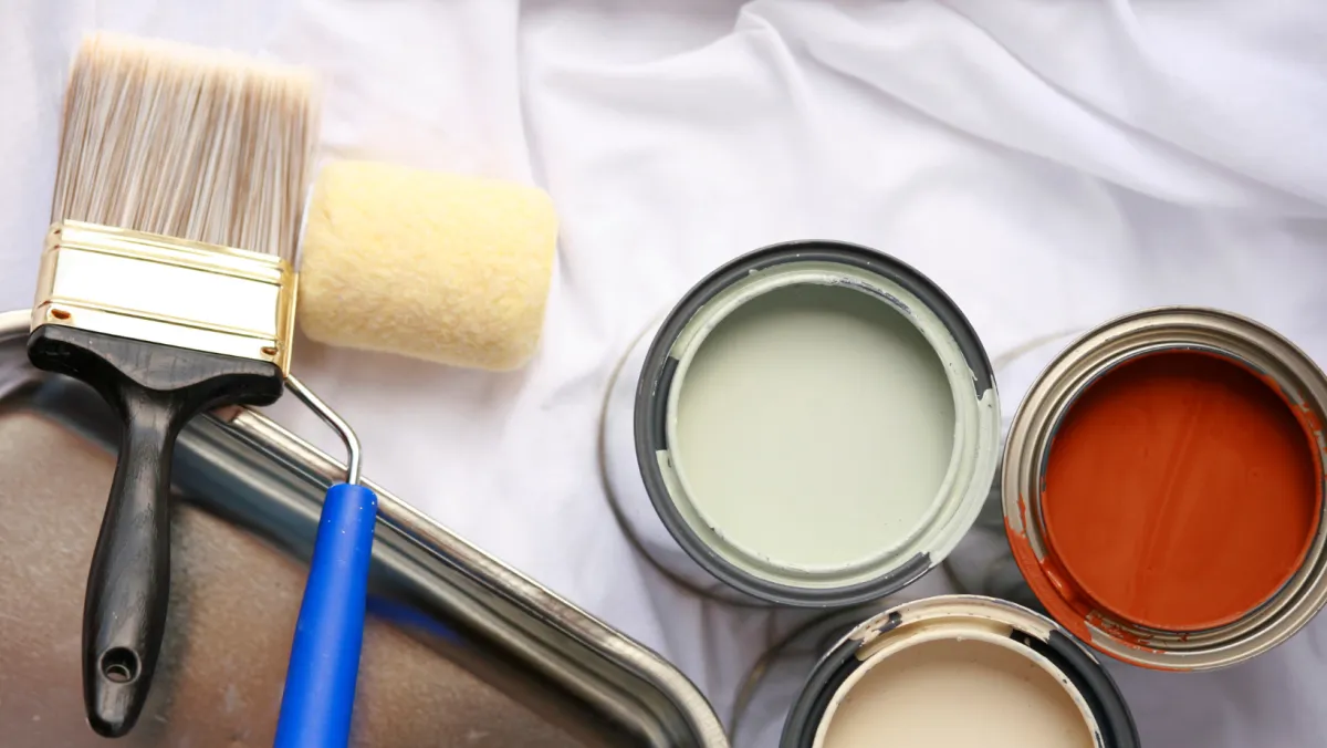 Photo of a few cans of paint and brushes.