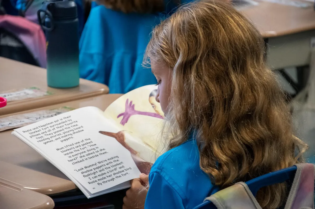 Young readers at a classroom table with stacks of children's books ready for distribution.