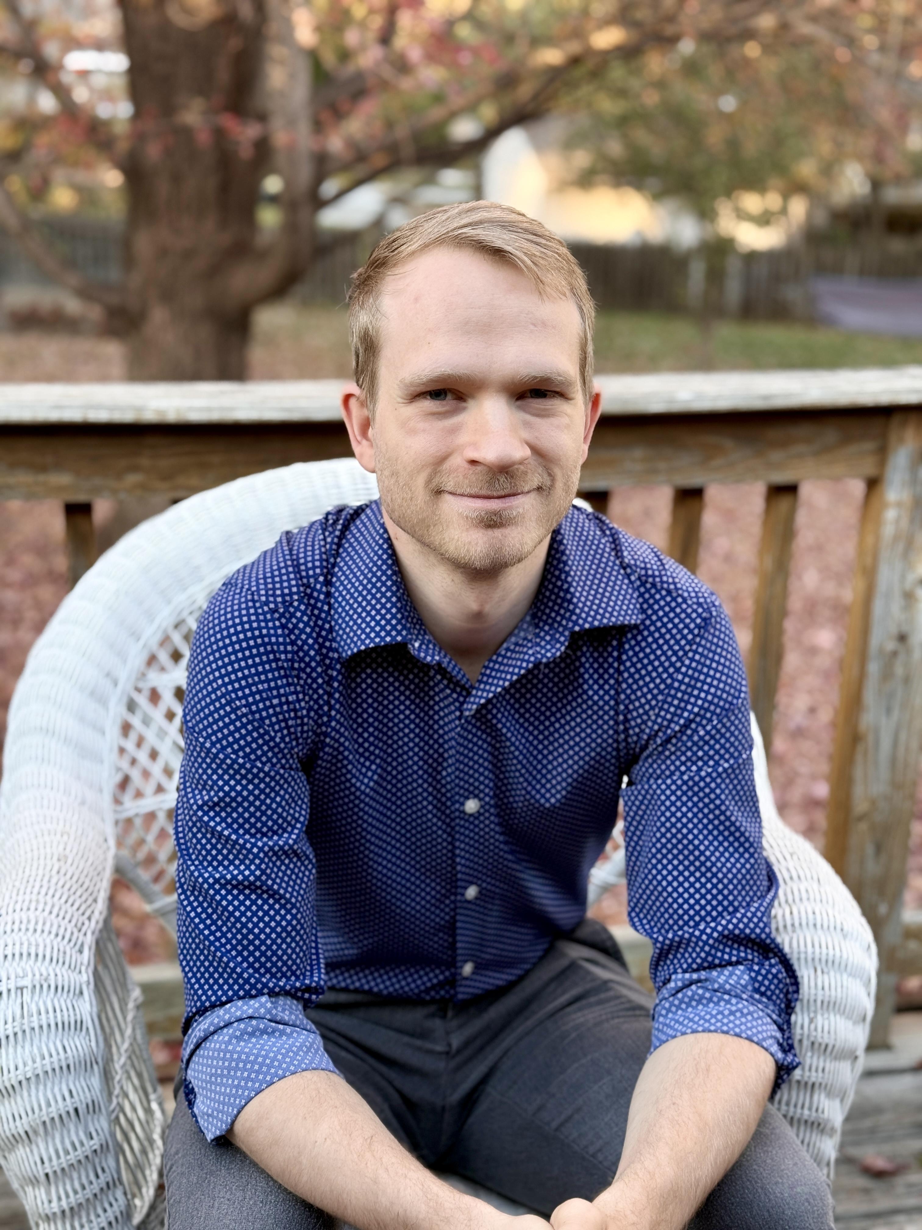 A professional financial consultant, mid-40s, with a warm smile, seated at a desk with business books and a laptop, in a bright, inviting workspace. The background features subtle blue tones and motivational quotes on the wall.